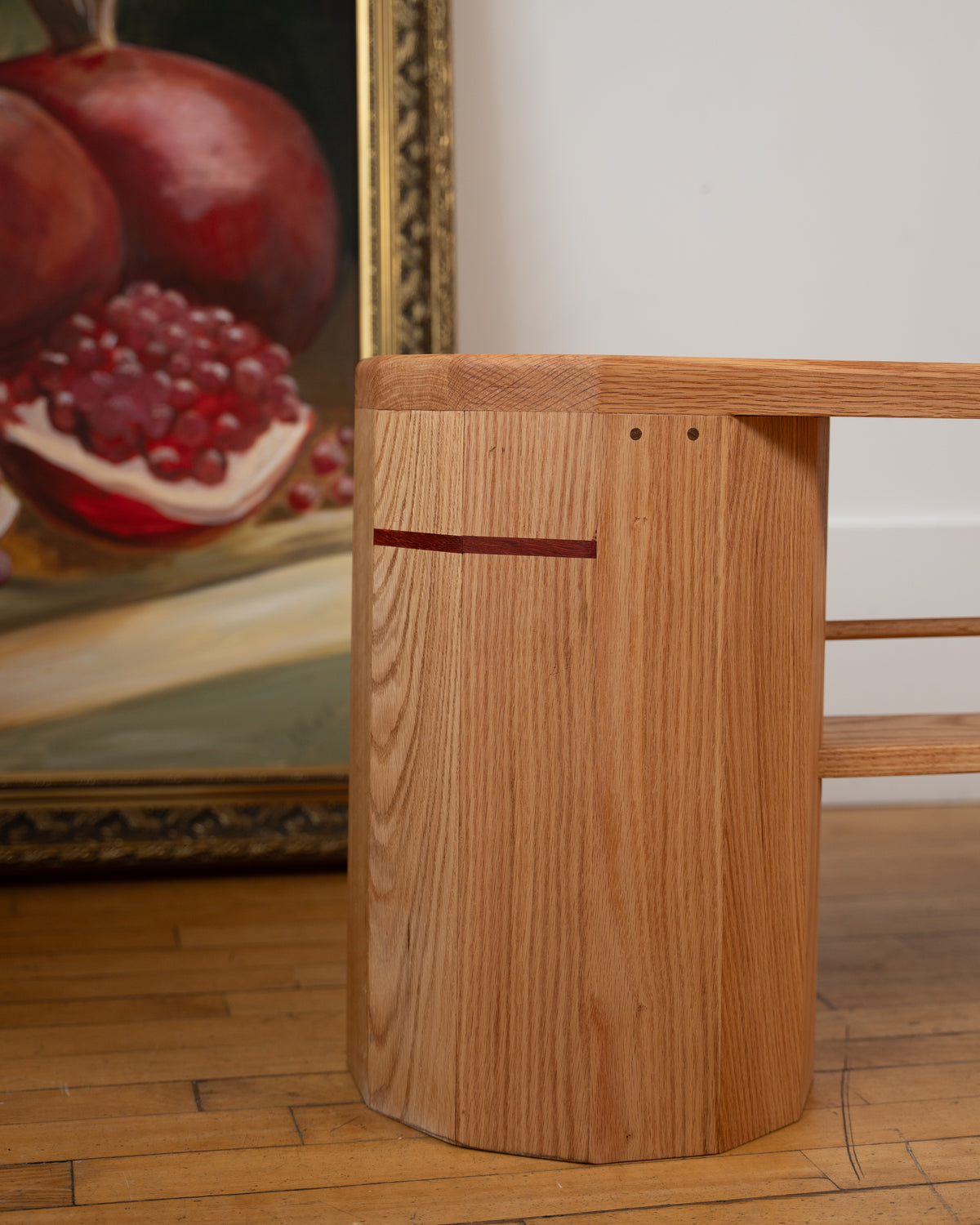 Close-up of the signature red line on the red oak column of the handmade iB-v2 Dual Column Bench by Redline Design