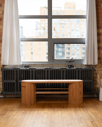 iB-v2 Dual Column Bench in red oak in a room with exposed brick, a large window and a cast iron radiator